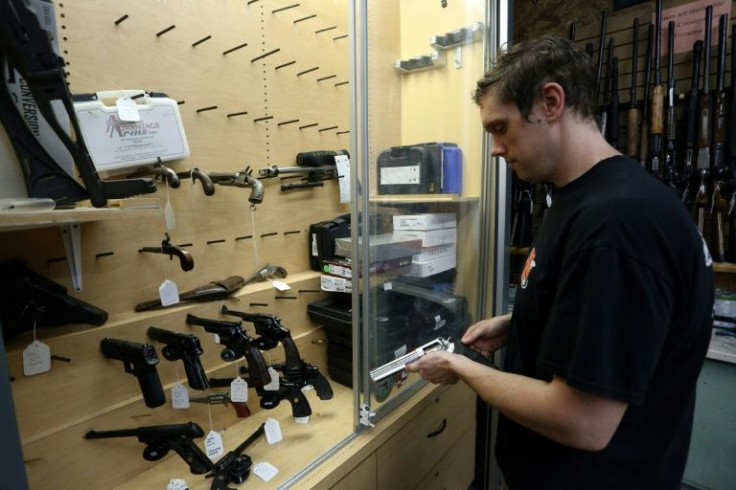 Salesman Chris Ruegg takes a handgun from a nearly empty display case at That Hunting Store in Ottawa, Canada