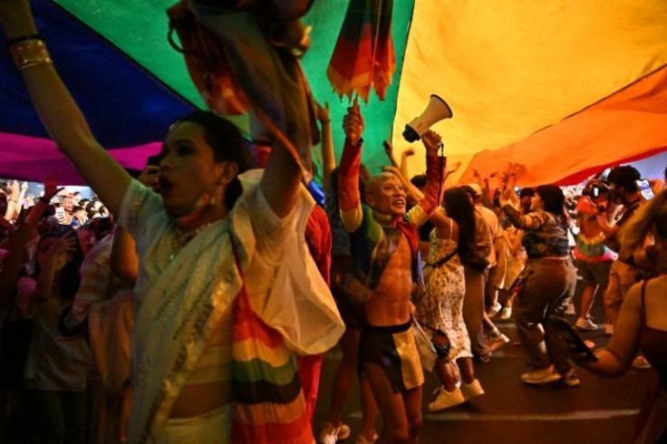 People celebrate under a giant rainbow flag during the Pride March in Bangkok on June 5, 2022