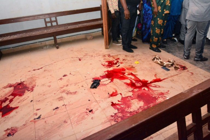 People stand near the blood the stained floor after an attack by gunmen at St. Francis Catholic Church in Owo town