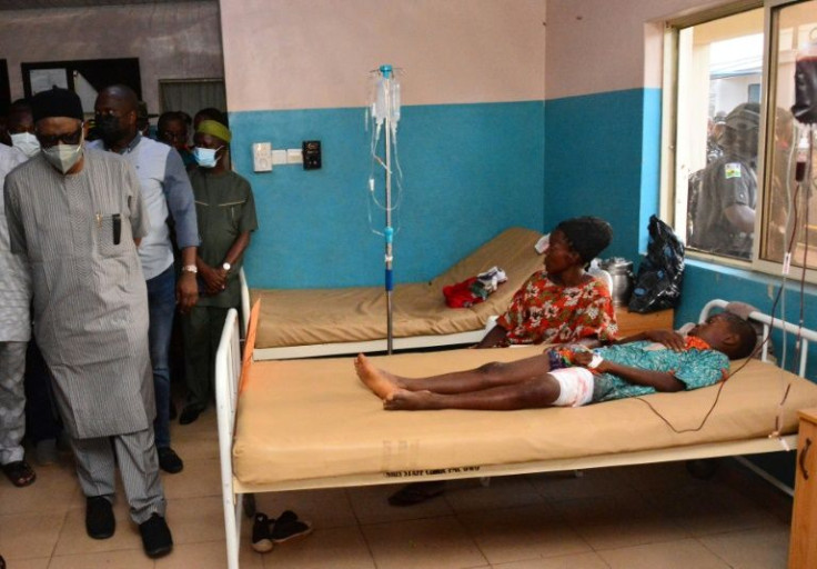 State officials walk past victims being treated for wounds following an attack by gunmen at St. Francis Catholic Church