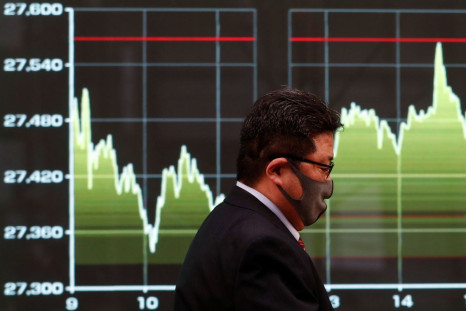 A man walks past a screen displaying a graph showing recent Nikkei share average movements outside a brokerage in Tokyo, Japan, December 30, 2020. 
