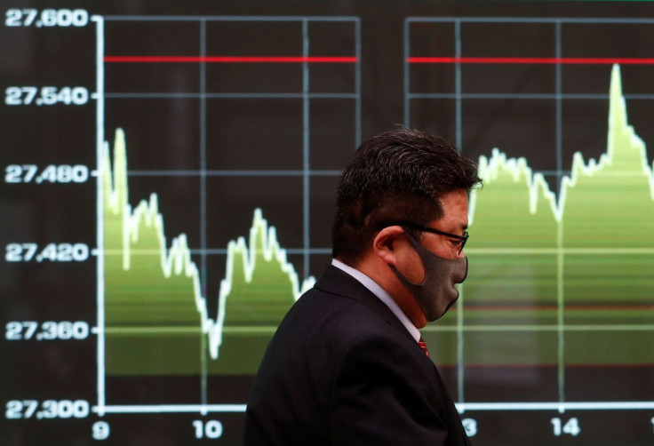 A man walks past a screen displaying a graph showing recent Nikkei share average movements outside a brokerage in Tokyo, Japan, December 30, 2020. 