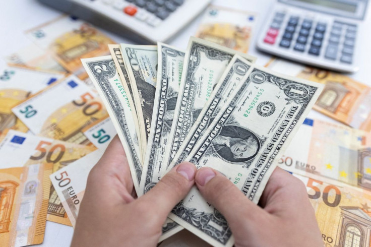 Woman holds U.S. dollar banknotes in front of Euro banknotes in this illustration taken May 30, 2022.