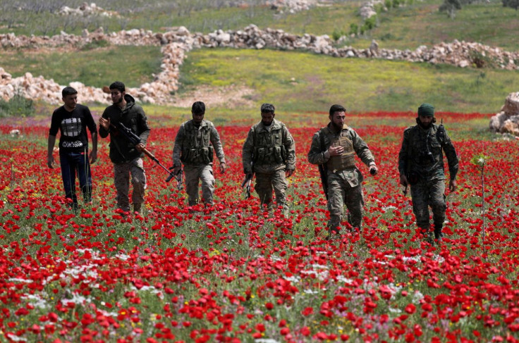Turkey-backed Syrian rebel fighters walk in a field of flowers in Jabal al-Zawiya in Idlib's southern countryside, amid concerns about the spread of the coronavirus disease (COVID-19), Syria April 15, 2020. Picture taken April 15, 2020.