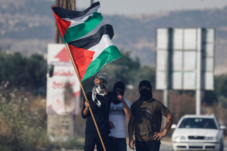 Palestinians hold the Palestinian flag during a protest over tensions in Jerusalem's Al-Aqsa Mosque, at Huwara checkpoint, near Nablus in the Israeli-occupied West Bank May 29, 2022.