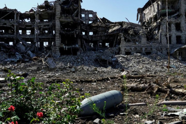 An unexploded bomb lies in front of a destroyed building in Mariupol, some of whose residents say they were forced to evacuate to Russia in what Kyiv dubs "deportations"