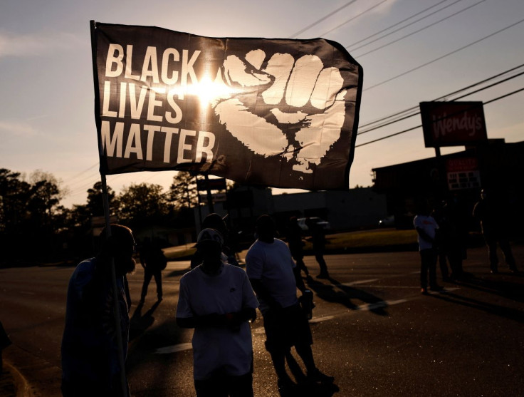 The setting sun shines through a Black Lives Matter flag as protesters occupy a busy intersection a week after Andrew Brown Jr. was killed by sheriffâs deputies in Elizabeth City, North Carolina, U.S. April 28, 2021.
