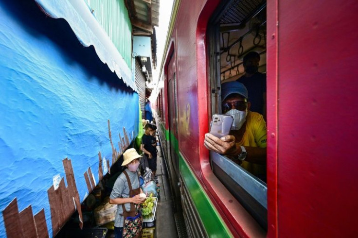 A train passenger takes a snap while passing through Thailand's Mae Klong railway market