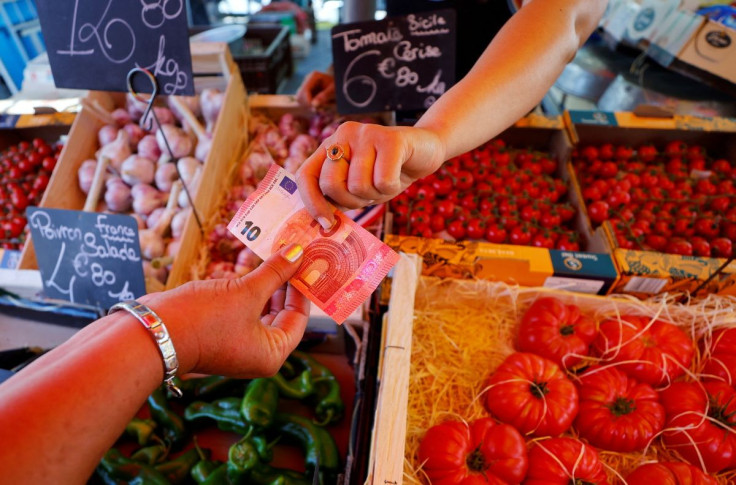 A shopper pays with a ten Euro bank note at a local market in Nice, France, June 7, 2022.  