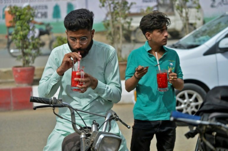 Two men in Karachi drink glasses of Rooh Afza, a popular drink in Pakistan's summer season