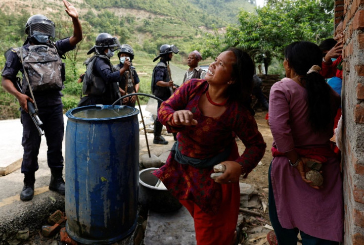 A woman hurls a stone at garbage trucks heading towards the dumping site as locals from a village near the dumping site protest against garbage being dumped in their area by obstructing garbage trucks from reaching the site at the outskirts of Kathmandu,
