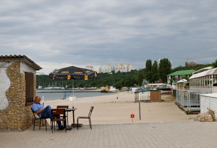 A man sits beside a closed off beach in Odesa, Ukraine, June 6, 2022.
