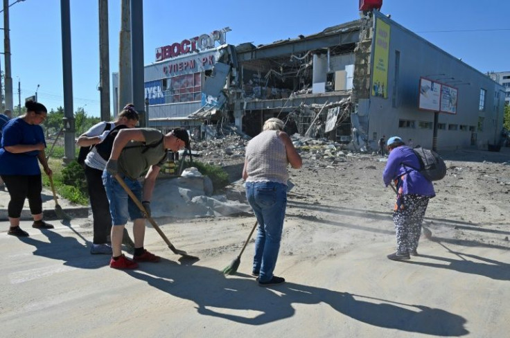 Communal workers clean up the rubble of a supermarket, partially destroyed by a missile attack on the southeastern outskirts of the Ukrainian city of Kharkiv