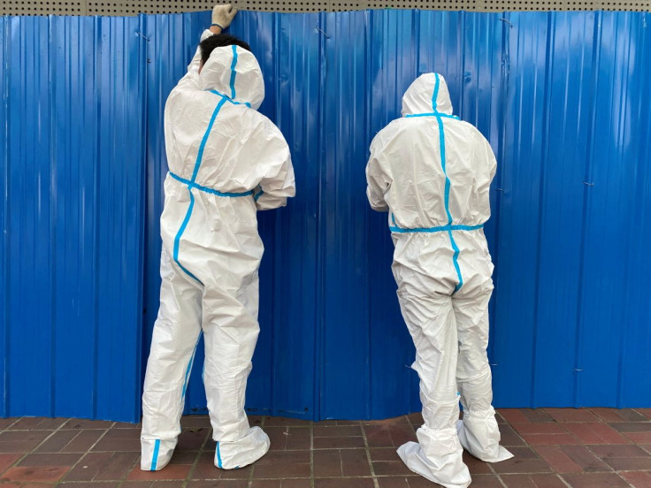 Workers in protective suits set up barriers outside a building, following the coronavirus disease (COVID-19) outbreak, in Shanghai, China June 9, 2022. 