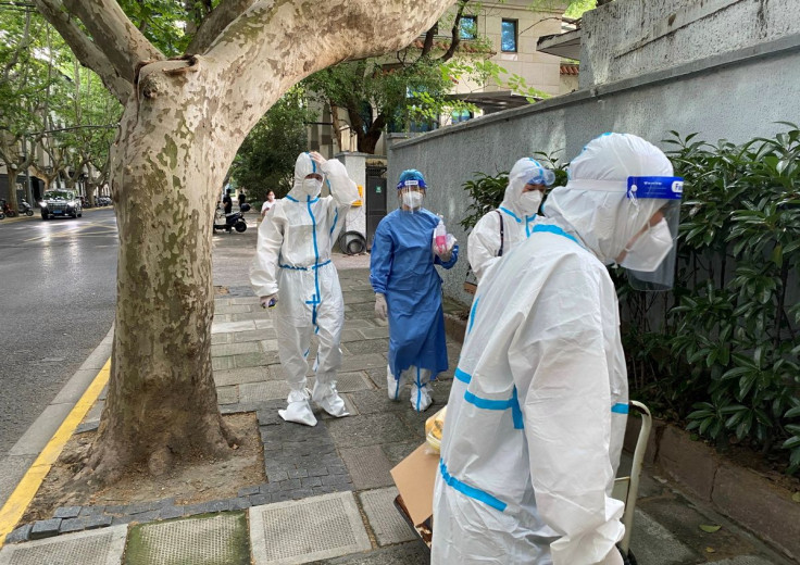 Workers in protective suits walk on a street, following the coronavirus disease (COVID-19) outbreak, in Shanghai, China June 9, 2022.