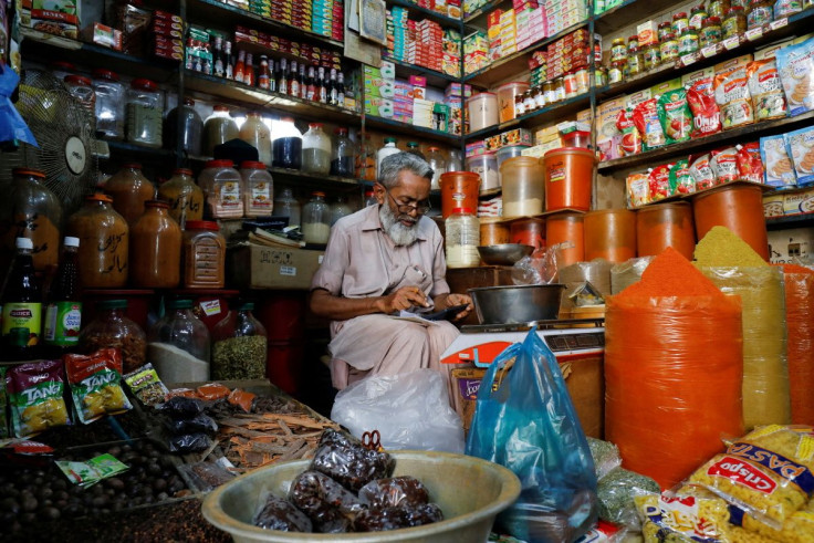 A shopkeeper uses a calculator while selling spices and grocery items along a shop in Karachi, Pakistan June 11, 2021. 