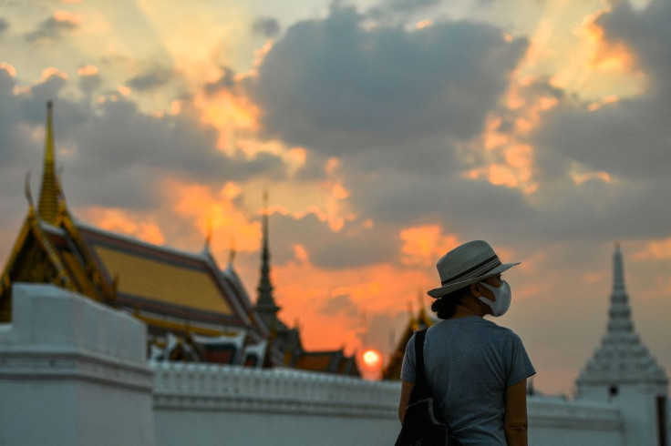A tourist wears a face mask to prevent spread of the coronavirus disease (COVID-19) during sunset near the Grand Palace in Bangkok, Thailand, January 7, 2022. 