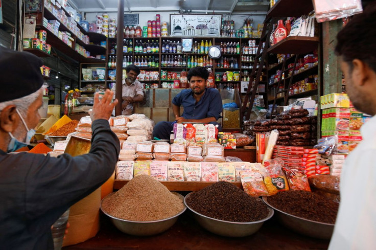 A shopkeeper listens to a customer as he sells groceries at a shop in a market in Karachi, Pakistan June 10, 2022. 