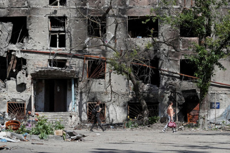 People walk past a residential building heavily damaged during Ukraine-Russia conflict in the southern port city of Mariupol, Ukraine May 30, 2022. 