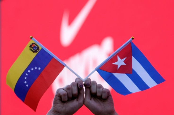 An activist carries Venezuelan and Cuban flags during a protest outside the Summit of the Americas at the LA Convention Center