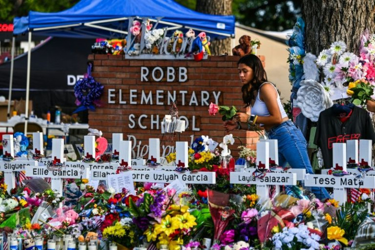 A girl lays flowers at a memorial at Robb Elementary School in Uvalde, Texas, on May 28, 2022