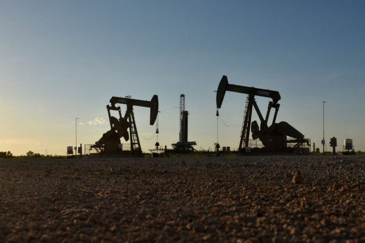 Pump jacks operate in front of a drilling rig in an oil field in Midland, Texas U.S. August 22, 2018. 
