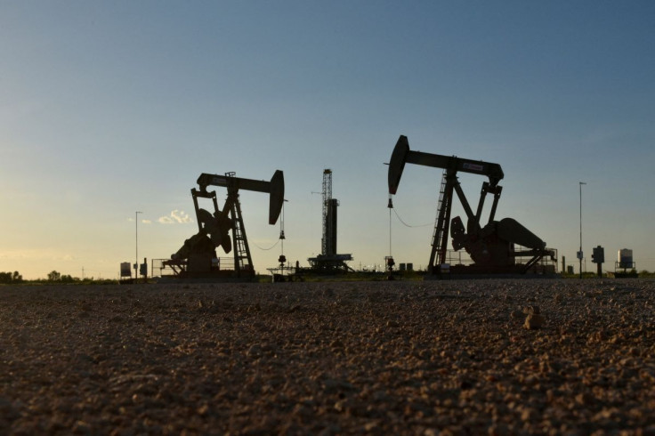 Pump jacks operate in front of a drilling rig in an oil field in Midland, Texas U.S. August 22, 2018.