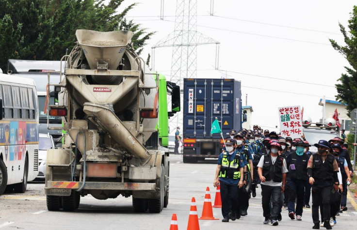 Trucks drive past members of the Cargo Truckers Solidarity union gathering in front of an inland containers depot in Uiwang, South Korea, June 13, 2022. Yonhap via REUTERS