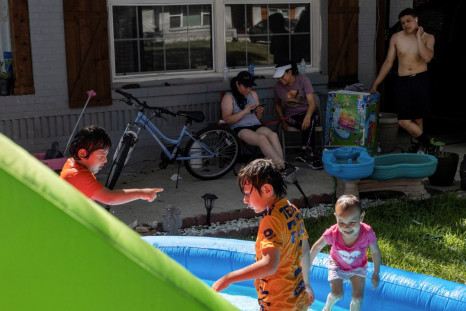Neighbors Maria Hernandez, Luisa Ortega and Issac Montelongo sit outside as they watch the kids play in water during a heatwave with expected temperatures of 102 F (39 C) in Dallas, Texas, U.S. June 12, 2022. Though the heat wave caused electricity use in