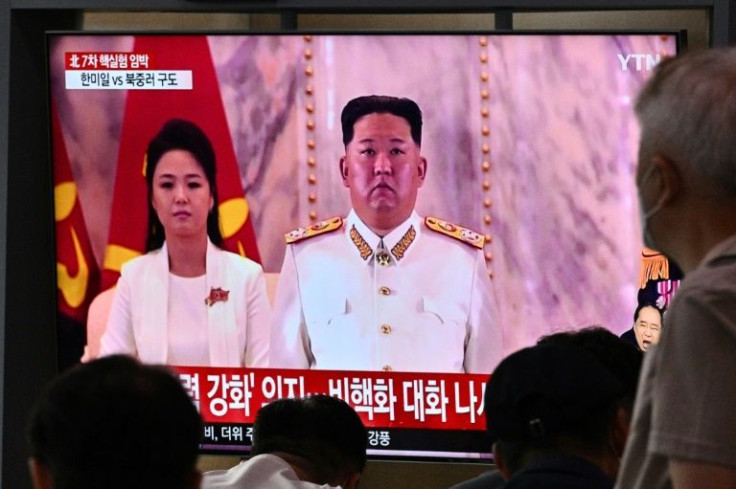 People in Seoul sit in front of a screen showing a news broadcast with file footage of North Korean leader Kim Jong-un and his wife Ri Sol-ju