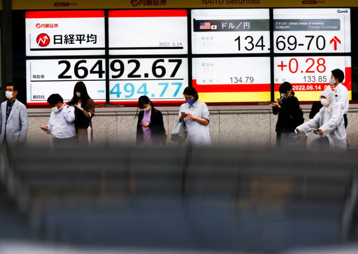 Passersby are seen in front of a screen displaying the Japanese yen exchange rate against the U.S. dollar and Nikkei share average in Tokyo, Japan June 14, 2022. 