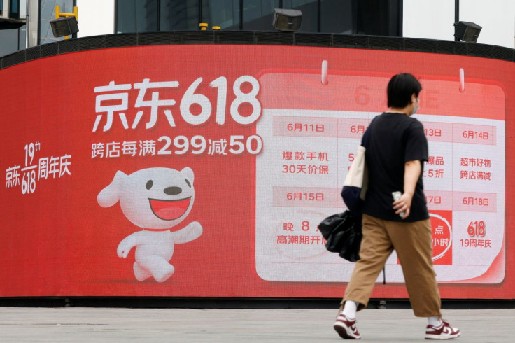 A resident, wearing a face mask following the coronavirus disease (COVID-19) outbreak, walks past a JD.com advertisement for the "618" shopping festival displayed outside a shopping mall in Beijing, China June 14, 2022.