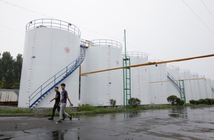 Men walk past oil tanks at the plant of Liangyou Industry and Trade Co., Ltd in Qufu, Shandong province, China July 4, 2018. 