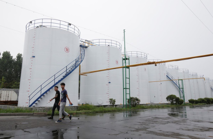 Men walk past oil tanks at the plant of Liangyou Industry and Trade Co., Ltd in Qufu, Shandong province, China July 4, 2018.