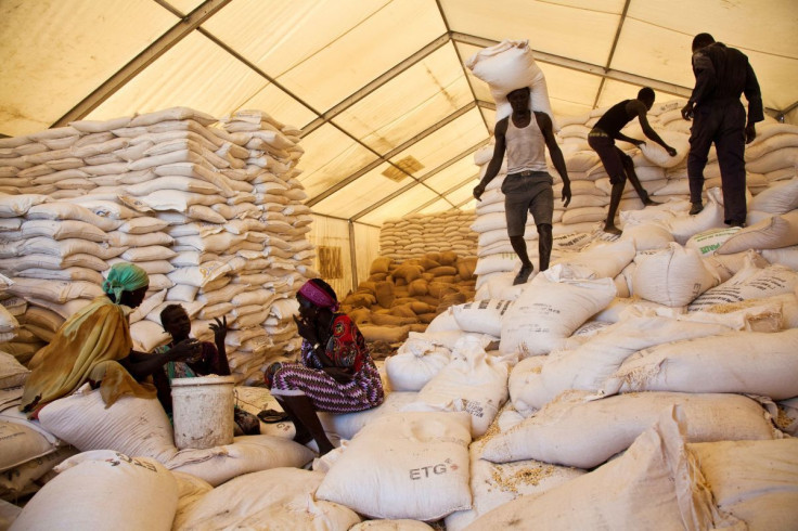 Men carry bags of food while women wait for their rations at the United Nations World Food Programme (WFP) food distribution site in Pibor, South Sudan, June 25, 2012.