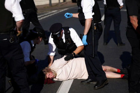 Police officers try to remove an activist blocking a road leading away from the Colnbrook Immigration Removal Centre during a protest against the British Government's plans to deport asylum seekers to Rwanda, near Heathrow airport in London, June 14, 2022