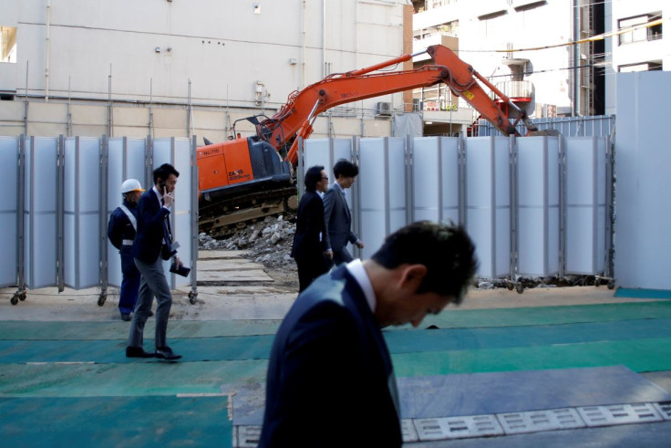 Businessmen walk past heavy machinery at a construction site in Tokyo's business district, Japan, January 16, 2017.    