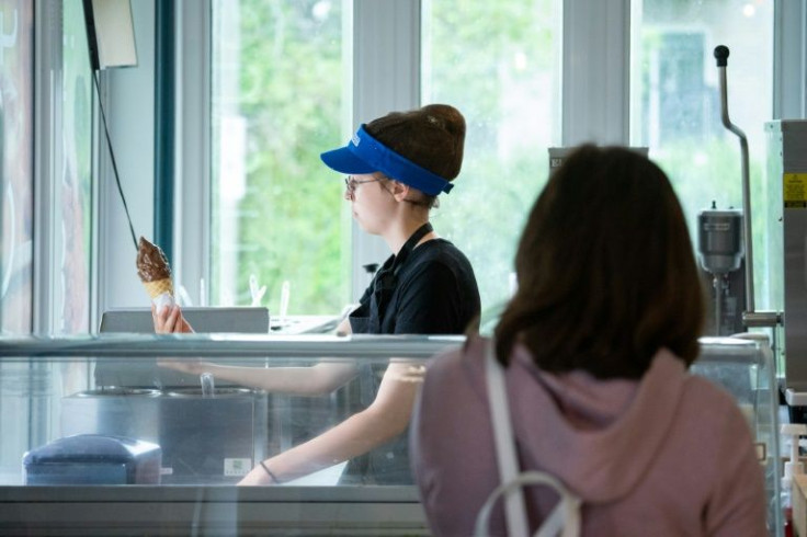 Sofia-Rose Adams, 13, dips a cone in chocolate for a waiting customer at the cafe and ice cream parlor where she works in Saint-Mathias-sur-Richelieu, Canada
