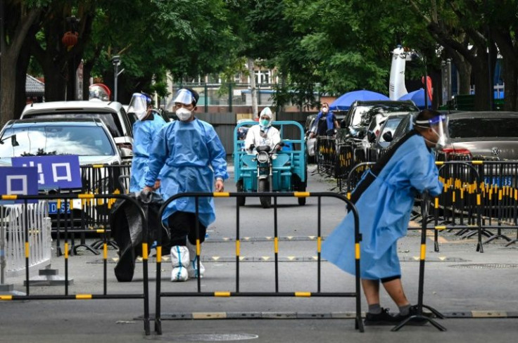 Workers and security guards in protective gear outside a locked down residential estate in Beijing