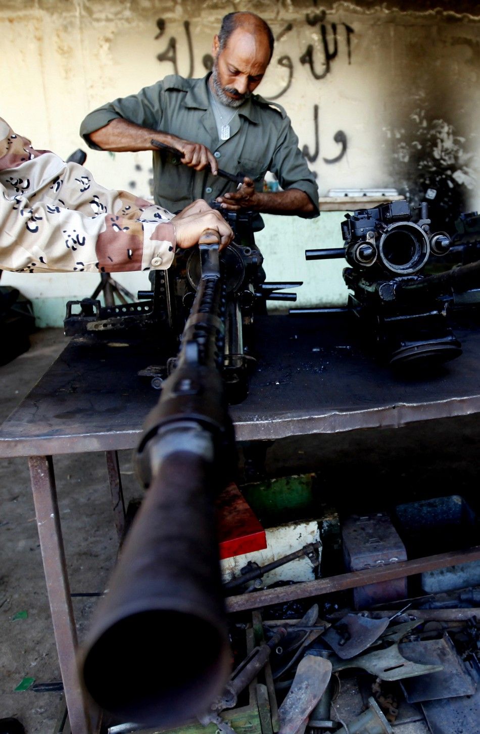 A rebel army officer fixes weapons taken from forces loyal to Libyan leader Muammar Gaddafi at a workshop in Benghaz