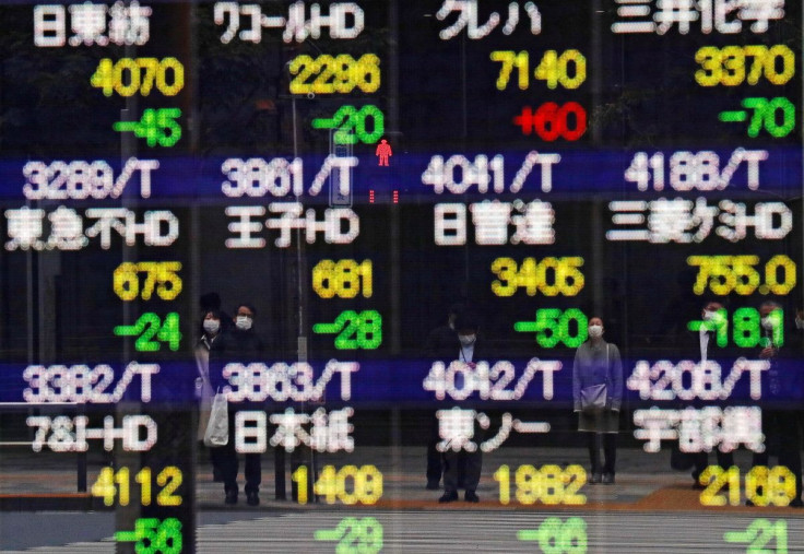 Pedestrians and a traffic light stop sign are reflected on a quotation board in Tokyo, Japan February 26, 2021.