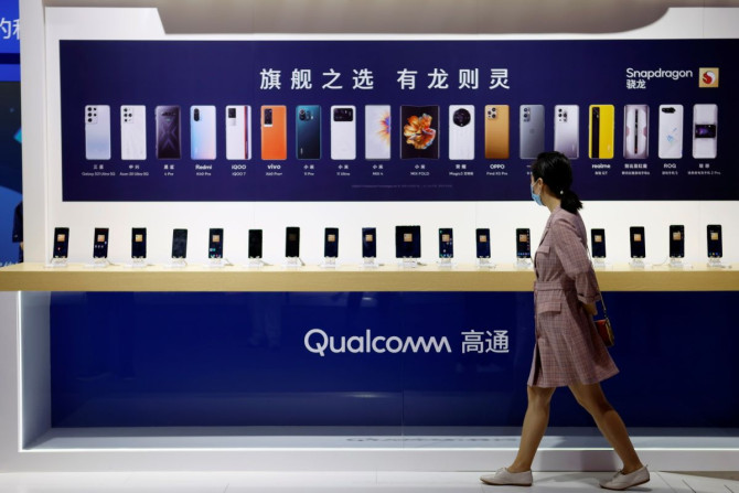 A woman walks past a counter displaying mobile phones at the Qualcomm booth during the 2021 China International Fair for Trade in Services (CIFTIS) in Beijing, China September 4, 2021. 