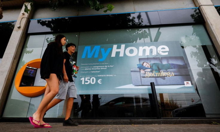 A couple walk past a Caixabank office in Montgat, near Barcelona, Spain, June 14, 2022. Picture taken June 14, 2022.