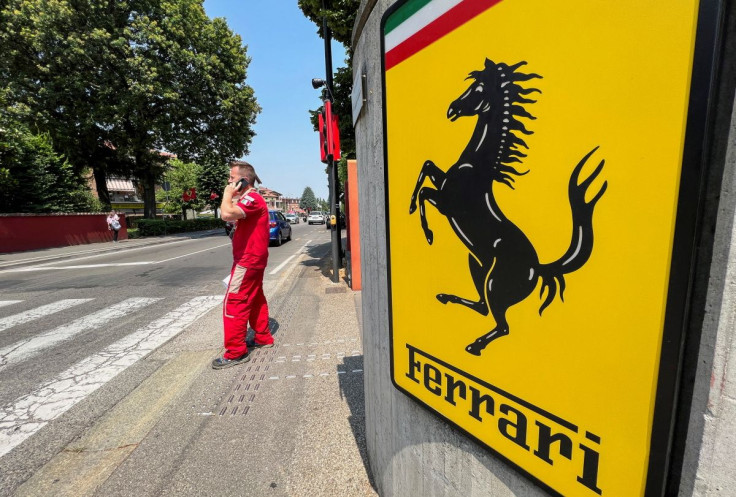 A Ferrari worker speaks on the phone next to the Ferrari logo outside the factory, in Maranello, Italy, June 15, 2022. 