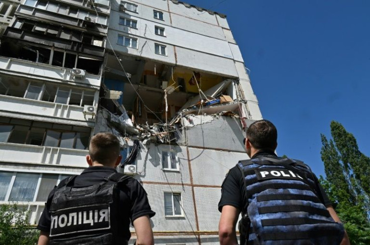 Ukrainian policemen look at a building partially destroyed by shelling in Kharkiv on June 16, 2022
