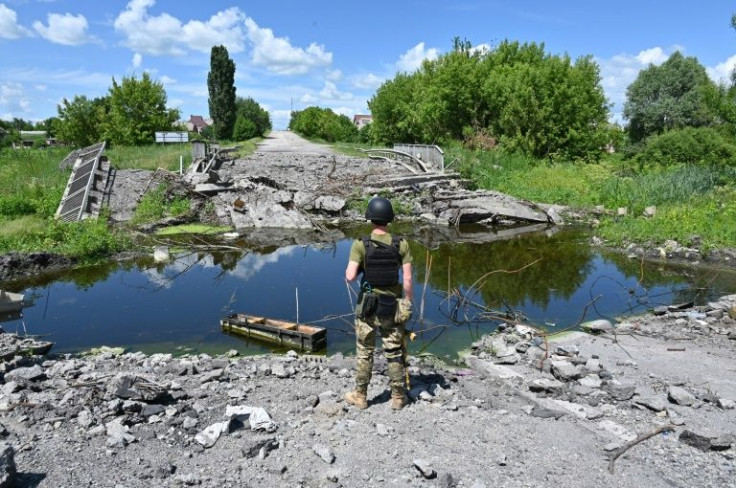 A Ukrainian serviceman looks at a blown-up bridge over the Lozovenka River near the village of Rus'ka Lozova near Kharkiv on June 16, 2022