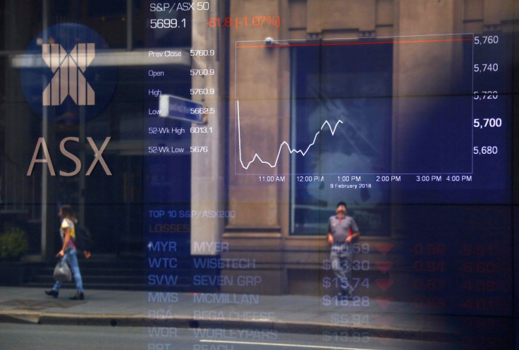 Pedestrians are reflected in a window in front of a board displaying stock prices at the Australian Securities Exchange (ASX) in Sydney, Australia, February 9, 2018.   