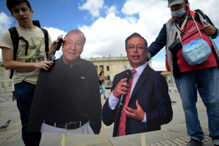 Men pose holding cardboard cutouts of Colombia's presidential candidates, Gustavo Petro (right) and Rodolfo Hernandez (left) in Bogota, on June 9, 2022