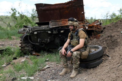 A Ukrainian serviceman sits next to a destroyed Russian tank not far from Lysychansk on Friday