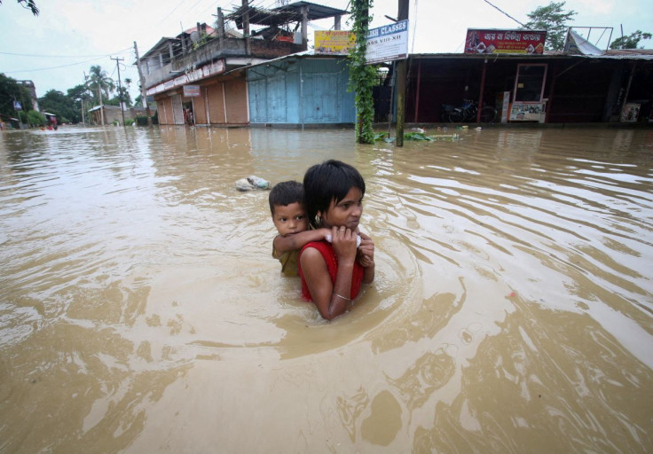 A girl carries her brother as she wades through a flooded road after heavy rains, on the outskirts of Agartala, India, June 18, 2022.